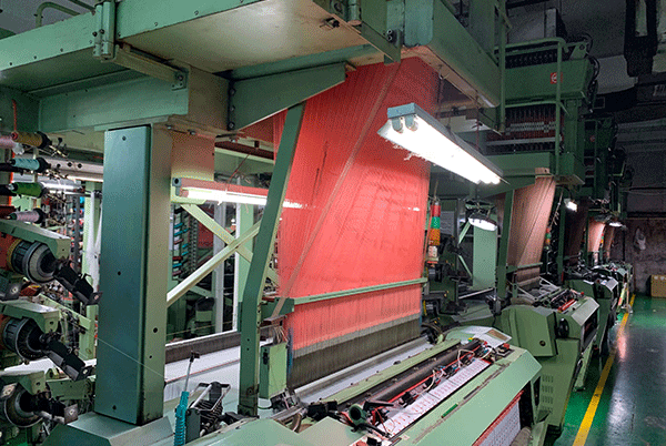 Industrial weaving loom producing high-density woven label fabric with consistent detail